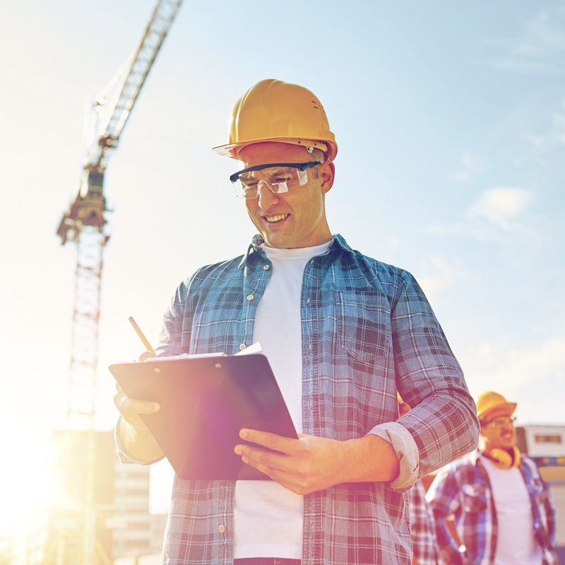 jefe de obra con casco de seguridad y gafas y grua de construccion de fondo